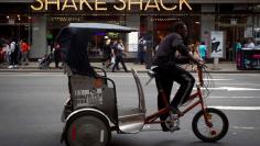 A pedicab rides past a Shake Shack restaurant in the Manhattan borough of New York August 15, 2014.    REUTERS/Carlo Allegri 