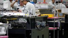 FILE PHOTO: Employees are seen by their workstations at a printed circuit board assembly factory in Singapore June 28, 2016. REUTERS/Edgar Su/File Photo