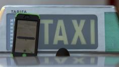 The car-sharing service app Uber on a smartphone next to a taxi sign is seen in this photo illustration taken in Madrid on December 10, 2014.  REUTERS/Sergio Perez   