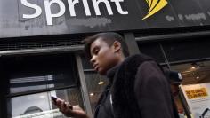 A woman uses her phone as she walks past a Sprint store in New York's financial district, October 15, 2012. REUTERS/Brendan McDermid 