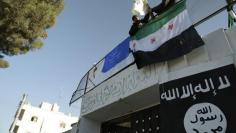 Free Syrian Army fighters erect the Syrian opposition flag atop a former base used by fighters from the Islamic State in Iraq and the Levant (ISIL), after it was captured by rival rebel forces in Manbij town in Aleppo January 8, 2014. REUTERS/Nashwan Marz