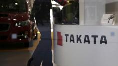 FILE PHOTO: A woman stands next to a logo of Takata Corp at a showroom for vehicles in Tokyo, Japan, November 6, 2015. REUTERS/Toru Hanai/File Photo 