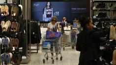 Customers shop in the F&F clothing department at a Tesco Extra supermarket in Watford, north of London August 8, 2013. REUTERS/Suzanne Plunkett