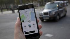 FILE PHOTO: A photo illustration shows the Uber app on a mobile telephone, as it is held up for a posed photograph, with a London Taxi in the background, in London, Britain November 10, 2017.  REUTERS/Simon Dawson/File Photo