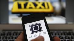 An illustration picture shows the logo of car-sharing service app Uber on a smartphone next to the picture of an official German taxi sign in Frankfurt, September 15, 2014. REUTERS/Kai Pfaffenbach