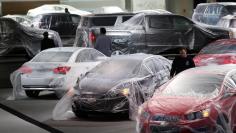 Vehicles are covered with protective wrap as workers prepare the General Motors automakers display ahead of the media preview of the North American International Auto Show at Cobo Center in Detroit, Michigan January 11, 2014.  REUTERS/Rebecca Cook 