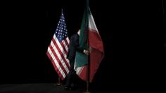 A staff member removes the Iranian flag from the stage after a group picture with foreign ministers and representatives of the U.S., Iran, China, Russia, Britain, Germany, France and the European Union during the Iran nuclear talks at the Vienna Internat