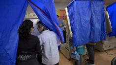 FILE PHOTO: An election worker helps a voter use the voting machine during the U.S. presidential election in Philadelphia, Pennsylvania, U.S. November 8, 2016.  REUTERS/Charles Mostoller