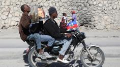 Protesters hold placards as they ride a motorbike during a protest in Port-au-Prince against reported comments made by U.S. President Donald Trump about Haiti,