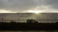 A U.S. Border Patrol vehicle drives by the 18-foot (five-metre) high rusty steel barrier along the U.S.-Mexico border at sunset in Brownsville, Texas September 2, 2014. REUTERS/Rick Wilking