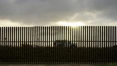 A U.S. Border Patrol vehicle drives by the 18-foot (five-metre) high rusty steel barrier along the U.S.-Mexico border at sunset in Brownsville, Texas September 2, 2014.  REUTERS/Rick Wilking 