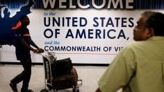 An international passenger (L) arrives at Dulles International Airport as a man (R) waits for loved ones to arrive in Dulles, Virginia, U.S. September 24, 2017. REUTERS/James Lawler Duggan