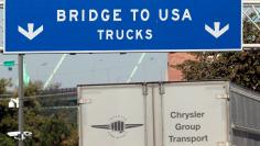 FILE PHOTO: A commercial automotive supplier truck passes under a sign leading to the Ambassador bridge crossing over to Detroit, Michigan from Windsor, Ontario