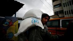 FILE PHOTO: A Palestinian man carries sacks of flour outside a United Nations food distribution center in Al-Shati refugee camp in Gaza City