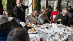 A waiter serves dessert to a table of men listening to Chinese millionaire Chen Guangbiao during a lunch he sponsored for hundreds of needy New Yorkers at Loeb Boathouse in New York's Central Park June 25, 2014. REUTERS/Lucas Jackson 