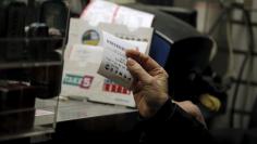 A customer purchases a Powerball lottery ticket at a news stand on Wall St. in New York January 13, 2016.  REUTERS/Brendan McDermid 