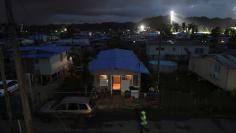 A house is lit up with the help of a generator next to houses in the dark after Hurricane Maria damaged the electrical grid in September, in Dorado, Puerto Rico January 15, 2018. REUTERS/Alvin Baez