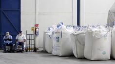 Workers sit next to bags containing sugar at the San Francisco Ameca sugar factory in the town of Ameca