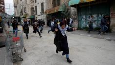 Palestinian demonstrators run for cover during clashes with Israeli troops at a protest against U.S. President Donald Trump's decision to recognise Jerusalem as the capital of Israel, in the West Bank city of Hebron, December 29, 2017. REUTERS/Mussa Qawa