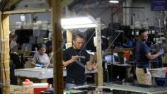 A worker looks over a glass window at Lippert Components in Goshen