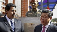 China's President Xi Jinping (R) speaks with Venezuela's President Nicolas Maduro in front of a statue of Venezuela's late president Hugo Chavez during a ceremony in Caracas in this July 21, 2014 file photo. REUTERS/Carlos Garcia Rawlins/Files