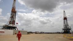 An oilfield worker walks next to drilling rigs at an oil well operated by Venezuela's state oil company PDVSA, in the oil rich Orinoco belt, near Morichal at the state of Monagas April 16, 2015. REUTERS/Carlos Garcia Rawlins
