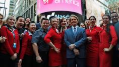 Virgin America Inc. President and Chief Executive Officer David Cush (3rd R) poses for photographs with Virgin America flight crews at the NASDAQ Market Site in New York, November 14, 2014. REUTERS/Mike Segar   