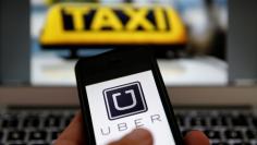 An illustration picture shows the logo of car-sharing service app Uber on a smartphone next to the picture of an official German taxi sign September 15, 2014.    REUTERS/Kai Pfaffenbach/Illustration/File Photo