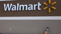 People walk past a Wal-Mart sign in Rogers, Arkansas June 4, 2009.  REUTERS/Jessica Rinaldi 