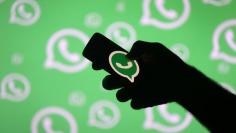 A man poses with a smartphone in front of displayed Whatsapp logo in this illustration September 14, 2017. REUTERS/Dado Ruvic  