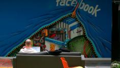 An employee works on a computer in front of a Facebook mural.  