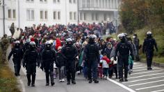 Slovenian police escort migrants walking towards the Austrian border near the village of Sentilj, Slovenia