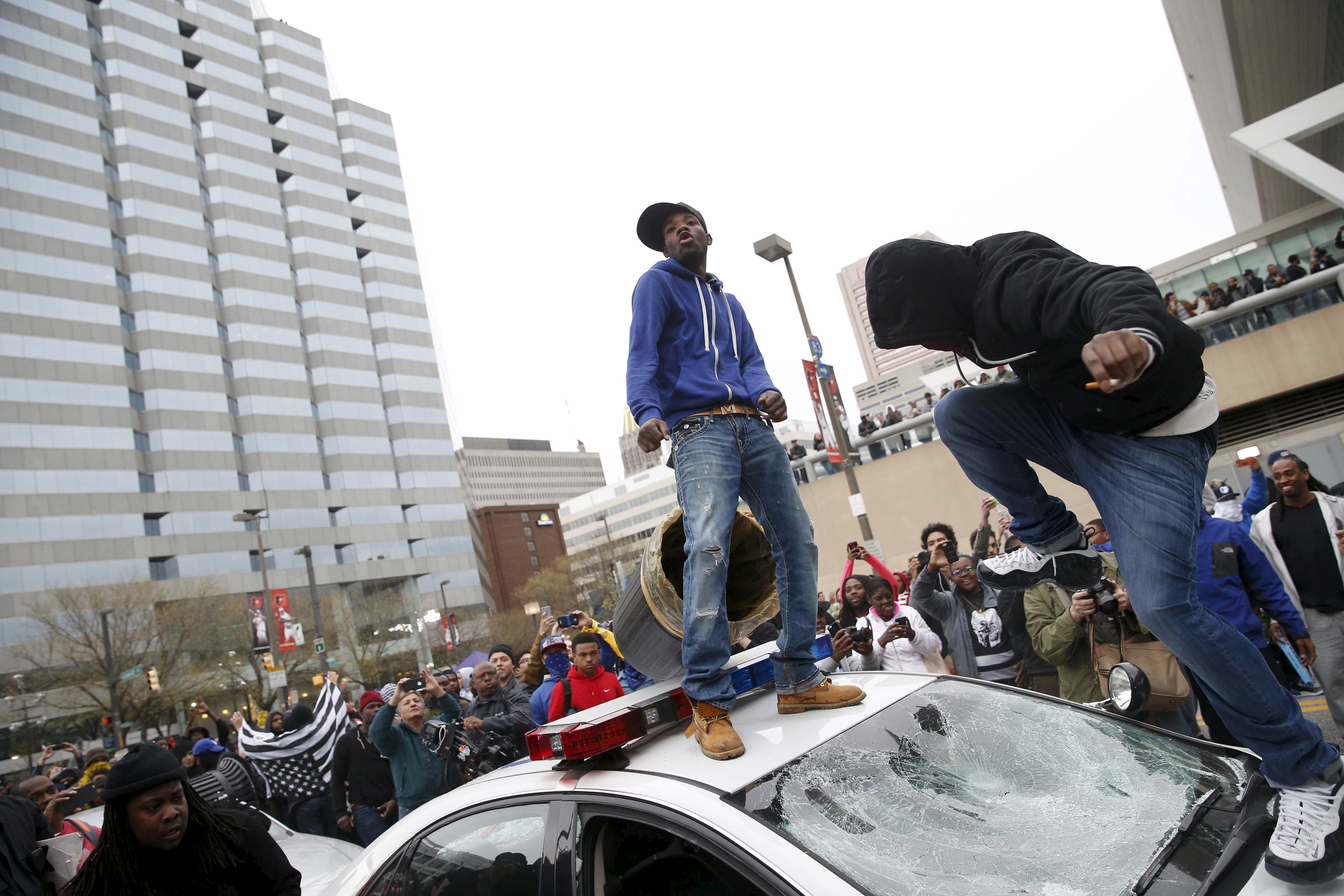 Protesters jump on a police car at a rally to protest the death of Freddie Gray who died following an arrest in Baltimore
