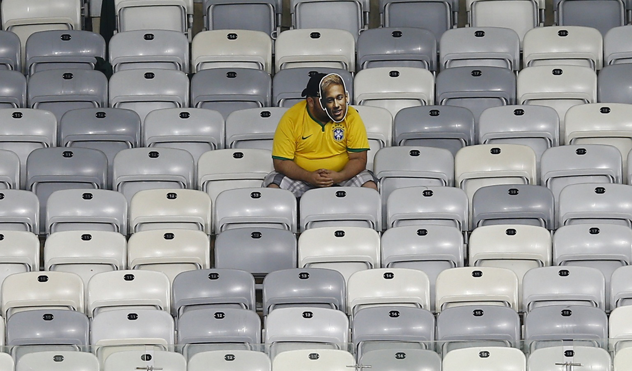 A Brazil fan wearing a mask depicting Neymar sits in the stands at the end of the 2014 World Cup semi-finals against Germany at the Mineirao stadium in Belo Horizonte