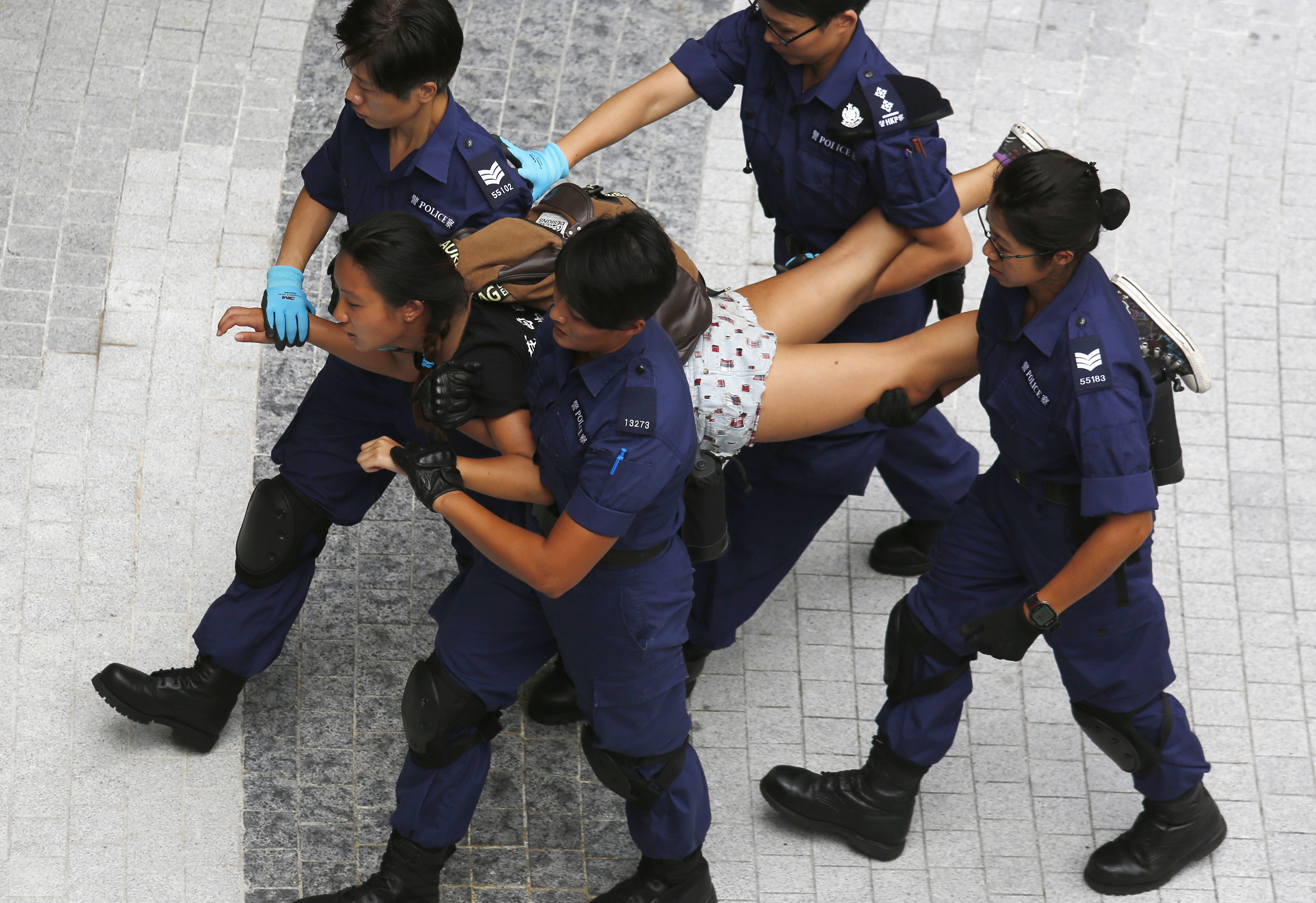 A protester is taken away by policewomen after storming into the government headquarters in Hong Kong
