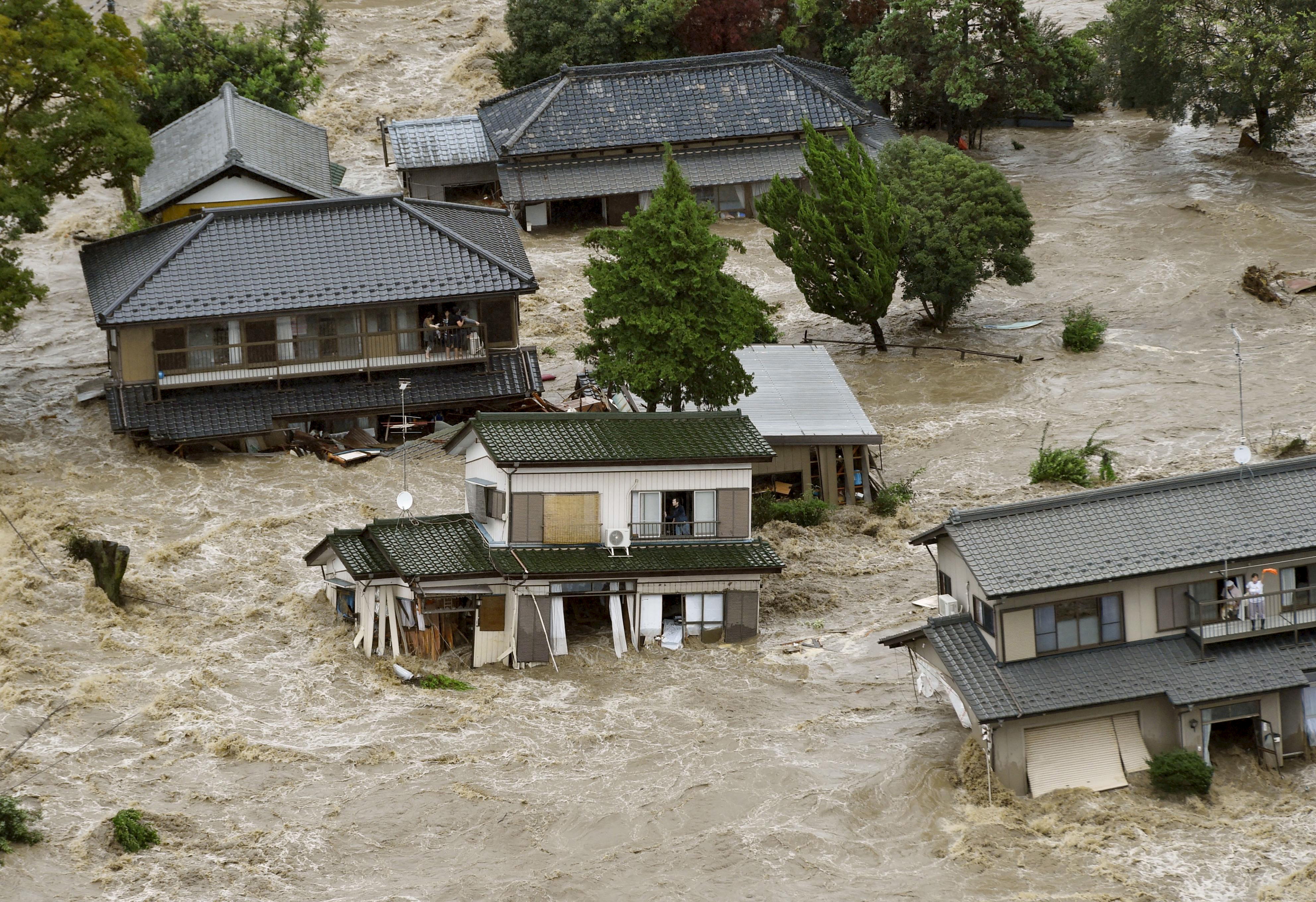 Residents are seen as they wait for rescue helicopters at a residential area flooded by the Kinugawa river, caused by typhoon Etau, in Joso