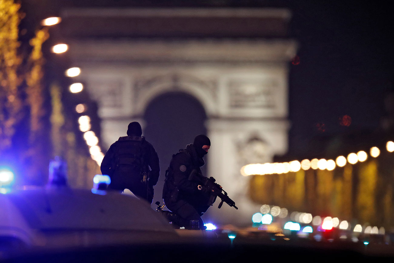 Masked police stand on top of their vehicle on the Champs Elysees Avenue after a shooting incident in Paris