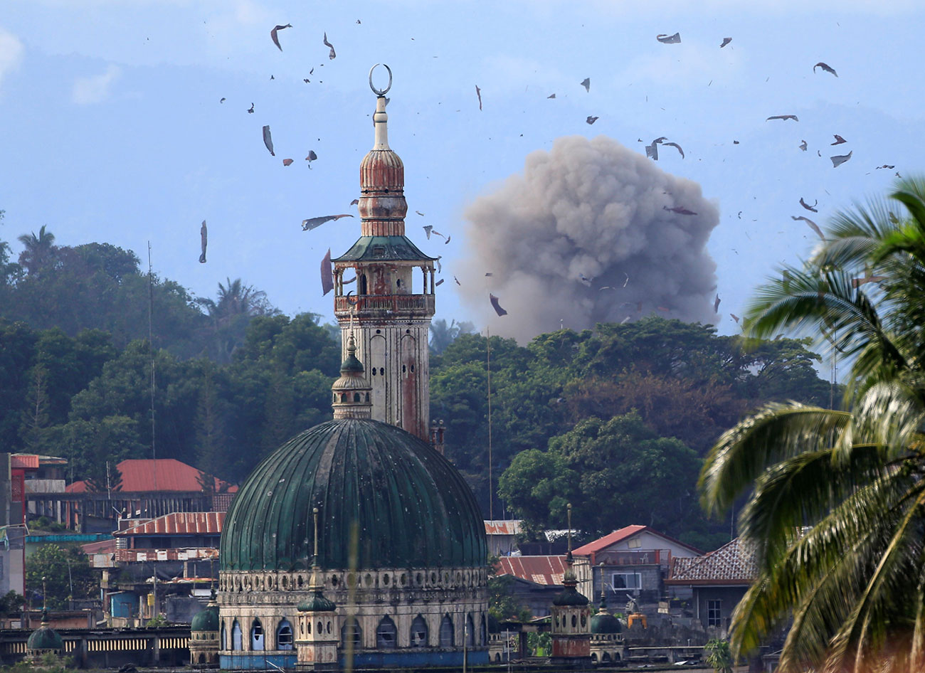 Debris and smoke billow are seen after an OV-10 Bronco aircraft released a bomb, during an airstrike, as government troops continue their assault against insurgents from the Maute group, who have taken over parts of Marawi city