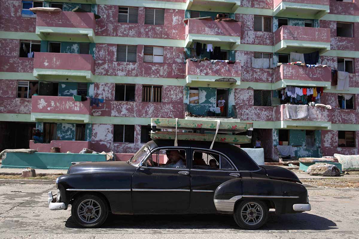 People transport beds on the roof of a vintage car after the passage of Hurricane Matthew in Baracoa