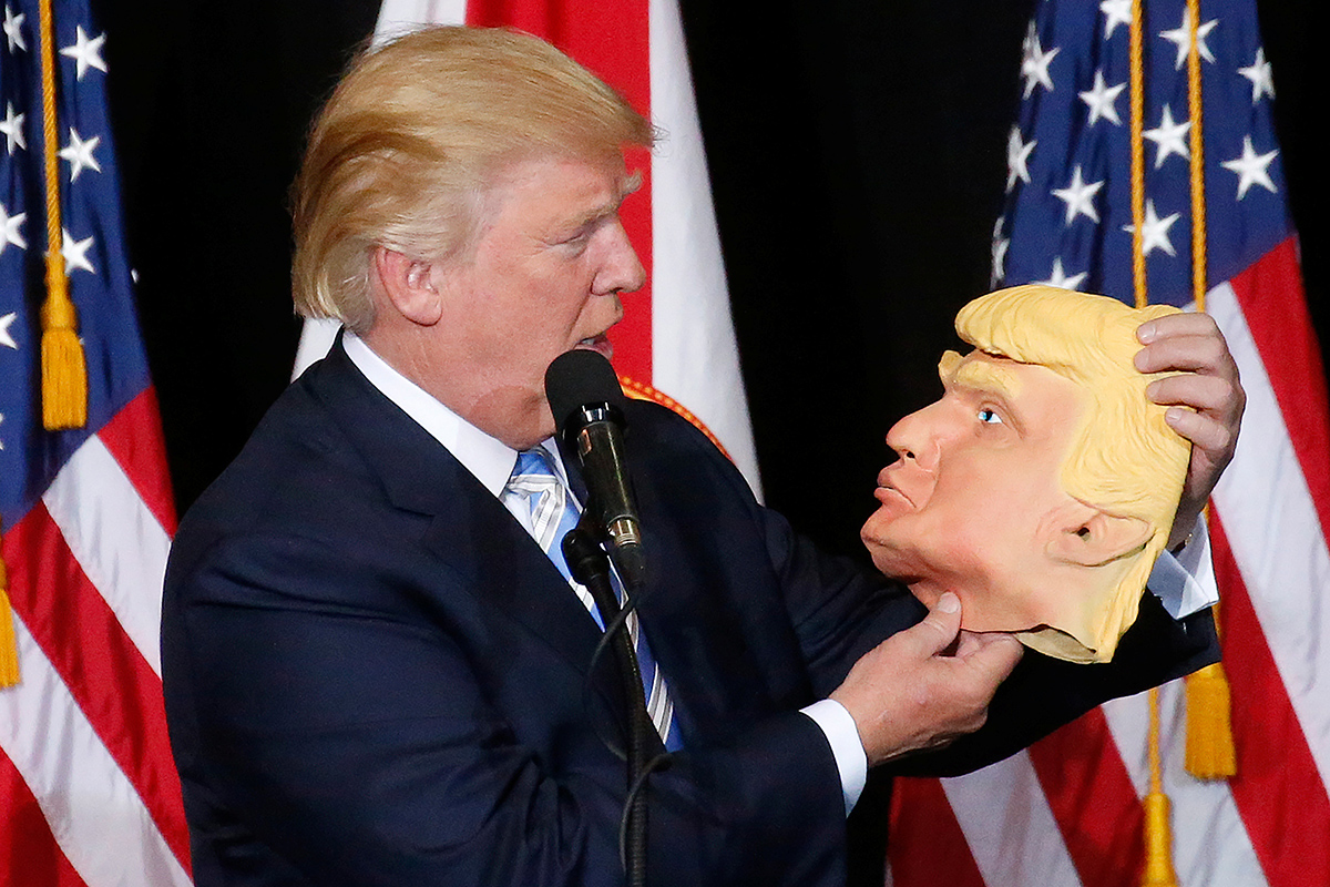 Republican presidential nominee Donald Trump looks at a mask of himself as he speaks during a campaign rally in Sarasota