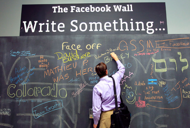 An employee writes a note on the message board at the new headquarters of Facebook in Menlo Park, California on January 11, 2012. The 57-acre campus, which formerly housed Sun Microsystems, features open work spaces for nearly 2,000 employees on the one m