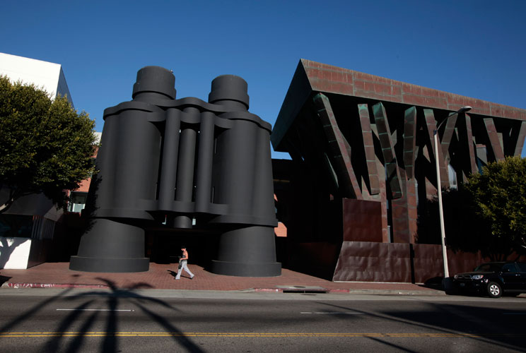 At an entrance of campus, a man walks past an iconic pair of giant binoculars designed by Claes Oldenburg and Coosje van Bruggen.