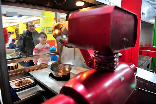 		<p>Customers watch a robot cooking dishes at the Robot Restaurant in Harbin, Heilongjiang province.</p>