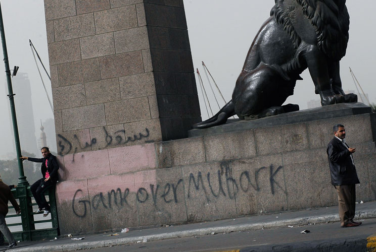 An Egyptian man stand in front of graffiti against President Hosni Mubarek on a bridge in central Cairo January 29, 2011 in Cairo, Egypt. Tens of thousands of demonstrators took to the streets across Egypt in Cairo, Suez, and Alexandria to call for the re