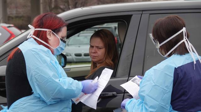 Healthcare workers with ChristianaCare test people with symptoms of the coronavirus in a drive-thru in the parking lot of Chase