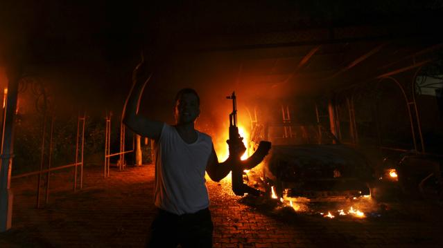 A protester reacts as the U.S. Consulate in Benghazi is seen in flames