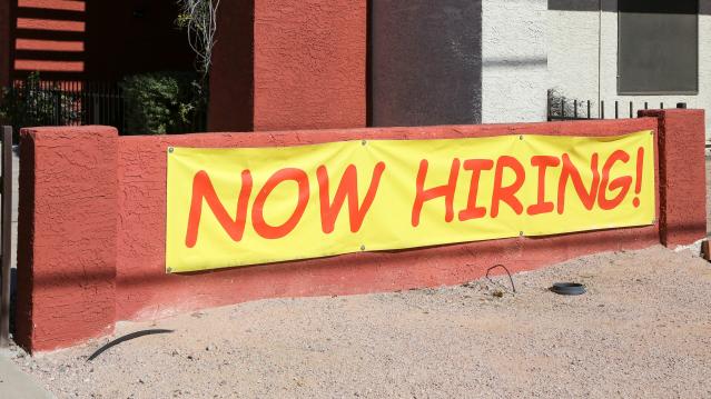 AZ: A Now Hiring Sign hangs outside to entice potential employees