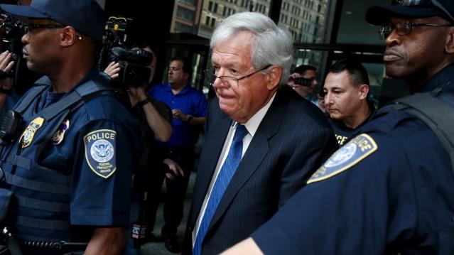 Former U.S. House of Representatives Speaker Dennis Hastert is surrounded by officers as he leaves federal court after pleading not guilty to federal charges of trying to hide large cash transactions and lying to the FBI in Chicago, Illinois, United State