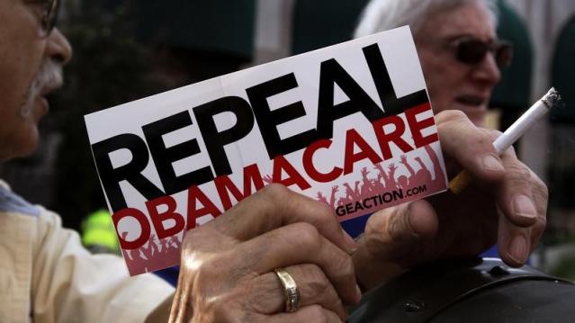 A small group of demonstrators stand outside of of a hotel before former South Carolina Senator Jim DeMint, president of the The Heritage Foundation, speaks at a &quot;Defund Obamacare Tour&quot; rally in Indianapolis, Indiana, U.S.  August 26, 2013.  REUTERS/Nate 