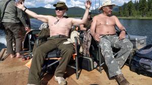 Russian President Vladimir Putin and Defence Minister Sergei Shoigu rest after fishing during the hunting and fishing trip which took place on August 1-3 in the republic of Tyva in southern Siberia